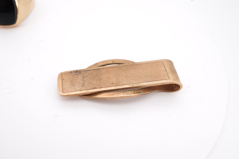 A 1980's 9ct gold tie clip, 39mm and a similar 9ct gold and black onyx set signet ring, gross weight 10 grams.